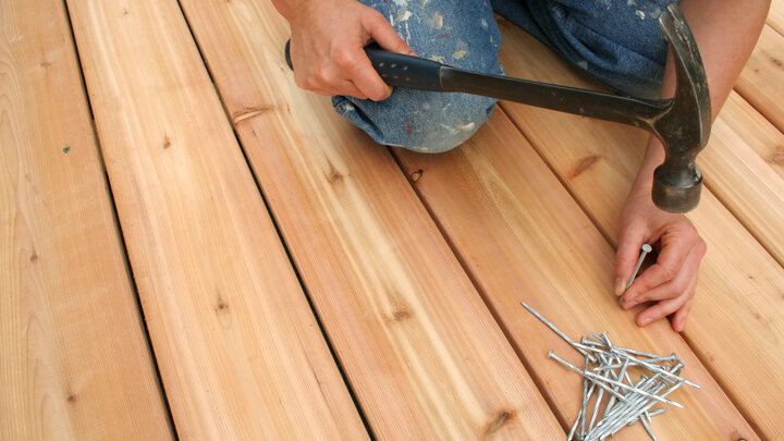 Person hammering nails on a deck