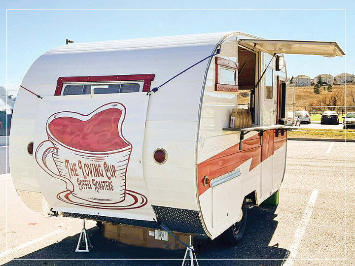 Retro coffee trailer with red and white accents, parked in a sunny outdoor setting.