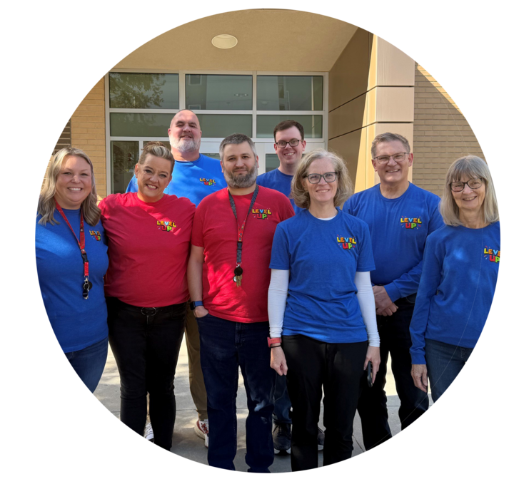 Group of smiling people in red and blue shirts standing outside a building.